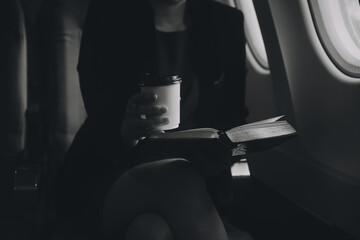 Blonde female tourist checking incoming notification on smartphone sitting on seat of airplane with netbook.Young businesswoman share media from telephone on laptop computer during plane flight