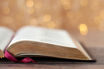Open holy bible book with golden bokeh light background. Close-up. Selective focus. Learning wisdom...
