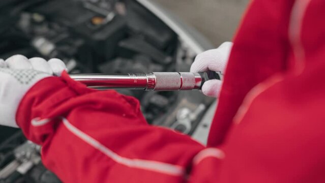 Mechanic adjusting torque wrench in car service to tighten bolts after replacing engine