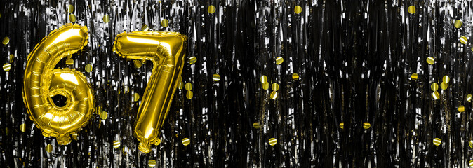 Gold foil balloon number number 67 on a background of black tinsel decoration. Birthday greeting...