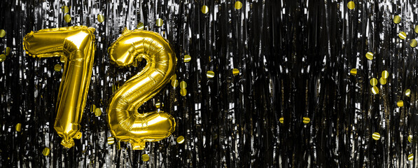 Gold foil balloon number number 72 on a background of black tinsel decoration. Birthday greeting...