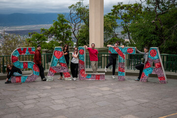 Grupo de amigos posando en el cartel turístico de la Ciudad de Salta - obrazy, fototapety, plakaty
