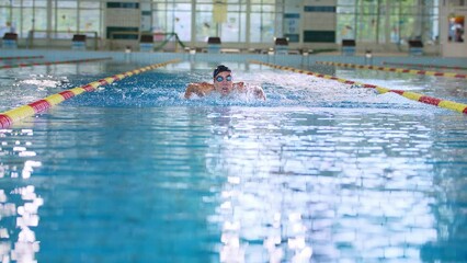 Front view of a female swimmer swimming butterfly style, a stroke performing in a competitive swimming. Success, power, and strength concept.