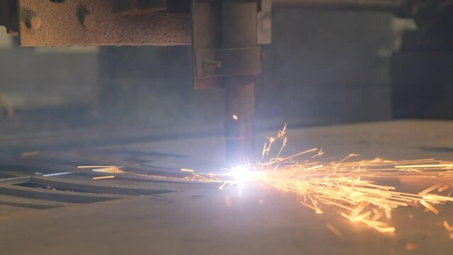 Close-up of a CNC machine cutting metal material for a heavy production line. Slow motion
