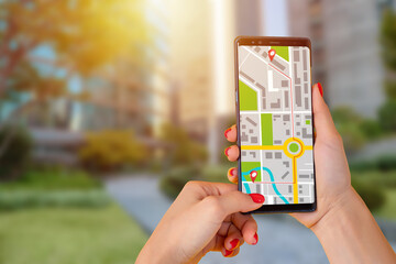 Mobile application with map. Smartphone in woman hands outdoor. Navigation application. Girl is...