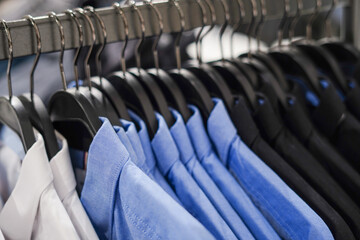 Fototapeta premium Men's clothing store, blue and black shirts on the hangers