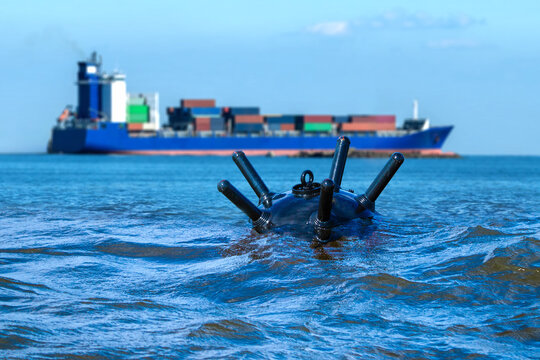 Underwater mine in sea. Cargo ship in ocean. Naval bomb threatens civilian ship. Underwater mine for naval blockade. Old sea bomb floated above water. Bomb for sea border protection