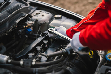 The mechanic tightens the spark plug into the cylinder head with a torque wrench - obrazy, fototapety, plakaty