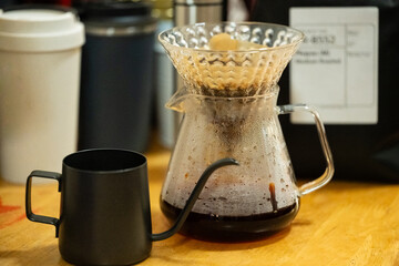 Coffee shop interior and accessories on the table.Coffee drip using pour over dripper and paper filter.Alternative coffee brewing method.