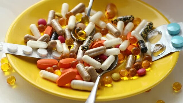 Rotating yellow plate with spoons full of medicines and supplements, Health concept, Excess consumption of medicines and dietary supplements, flat lay, white background