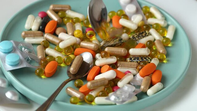 full of medicines blue plate and hand with spoon mixing pills, concept, Excess consumption of medicines and supplements, Hypochondria, close up