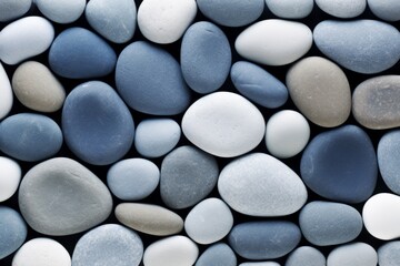 This high-resolution image showcases a beautiful arrangement of smooth sea pebbles in a variety of subtle earth tones ranging from soft whites to varying shades of blue and gray. The pebbles are