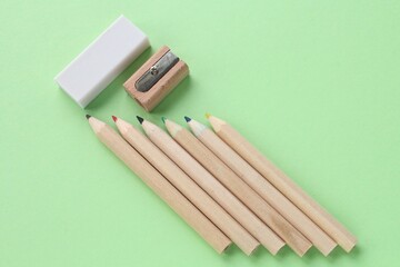 Pencil, wooden manual sharpener and eraser on green background. Back to school concept. Set of writing tools for education, creativity, drawing, hobby, art. Eco-friendly stationery