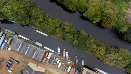 Arial view of barges and narrow boats docked at the canal edge with industrial buildings alongside...