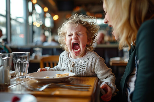Naklejki Toddler having a temper tantrum in a restaurant or cafe. Sad child screaming in anger in public. Kid misbehaving crying loudly.