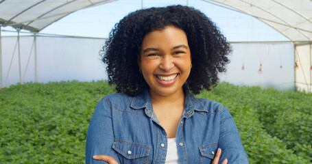 Close up portrait of smiling woman farmer standing in greenhouse tent, arms fold