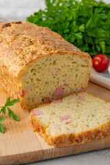 Zucchini bread with cheese, ham and fresh herbs on a wooden board on a gray background. Healthy food.