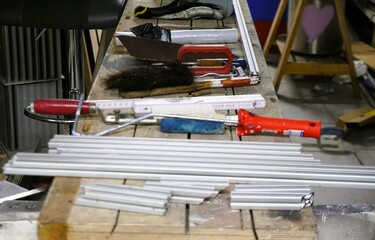 Fototapeta premium Holztisch mit silbernen Aluminiumstangen und Werkzeug in Werkstatt 