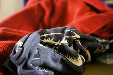 Blaugraues Baumwolltuch mit weißem Muster liegt vor rotem Pullover auf Ablage in Raum 