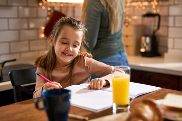 In the kitchen, a little preschooler enjoys breakfast and lets creativity flow, coloring with joy.