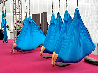 Yoga zur Entspannung: Riesige blaue Laken, an zwei Zipfeln befestigt, hängen von der Decke. Darin...