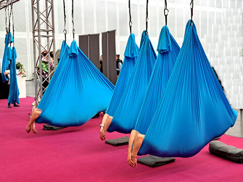 Yoga zur Entspannung: Riesige blaue Laken, an zwei Zipfeln befestigt, h&auml;ngen von der Decke. Darin liegt eine nicht sichtbare Person. Ihre H&auml;nde baumeln entspannt nach au&szlig;en. Gespenstisch bis lustig.