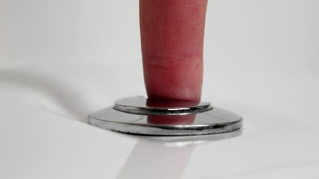 Pressing the toilet flush button in the restroom close up