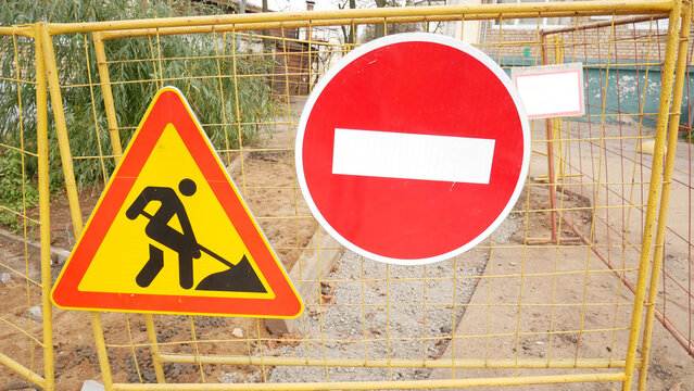 Stop and road works signs on a fence, construction and building industry.