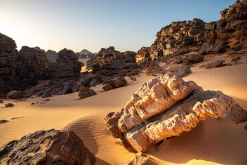 Landscape of Tadrart in the Sahara Desert, Algeria. Blocks of sandstone sculpted by erosion emerge from the yellow sand of Tadrart