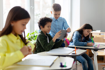 Schoolboys engrossed in using tablet during break after classes, creating a modern and interactive learning environment