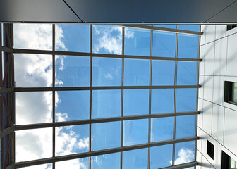 A blue sky with clouds through the glass roof.