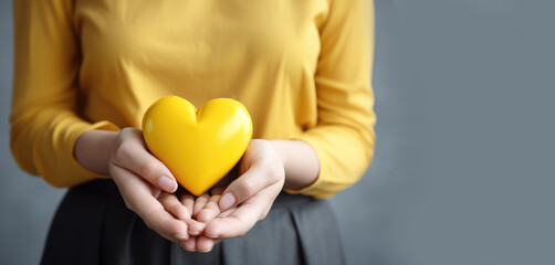 woman hold yellow heart for endometriosis awareness campaign, suicide prevention , a Childhood cancer.