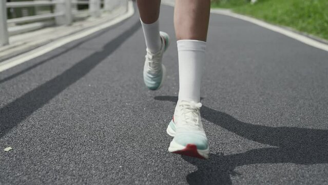 close-up shot of legs and feet of a female runner running on road