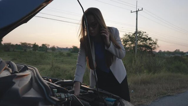 Asian Woman Car broken down on road.searching for repair service on smartphone worrying in stress. Car accident.