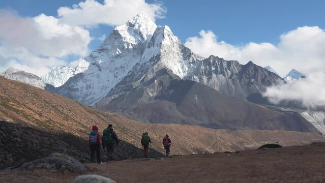Couple tourists with backpacks walking along hiking trail in gorge Himalayan mountains against highest peaks in world. Trekking to Everest base camp in Nepal. Moving towards goal and new experiences
