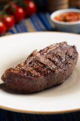 Roasted steak ,cherry tomatoes, salt and pepper on blue  wooden table.
