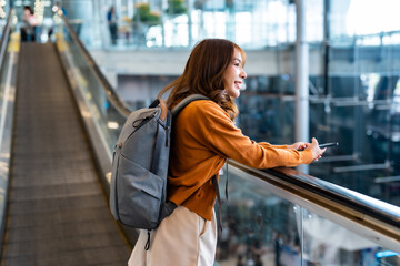 Young asian woman in international airport terminal or modern train station. Backpacker passenger...