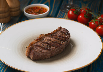 Roasted steak ,cherry tomatoes, salt and pepper on blue  wooden table.