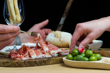 Close up of a selection of bites and appetizers being shared on a wooden table with a dark background