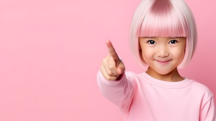 Horizontal shot pleased Asian child, points with two front fingers, shows blank space for your promotion, isolated on pink background. People, advertising concept, 