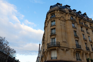 The facade of traditional French house with typical balconies and windows with Eiffel tower in the background . Paris.