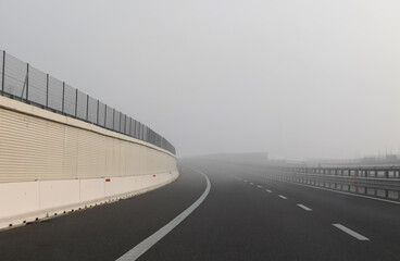 lane of motorway without cars but with a lot of dangerous fog which reduces visibility to motorists