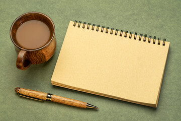 blank spiral sketchbook against textured paper with a cup of coffee, desktop flat lay