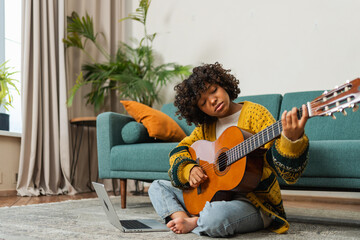 Blogger guitarist. Happy African American girl blogger playing guitar singing song recording vlog....
