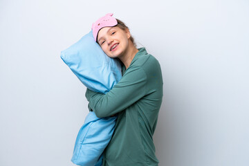 Teenager Russian girl isolated on white background in pajamas and holding a pillow with happy...