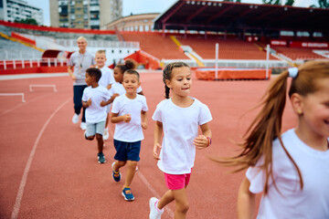 Group of kids running on track during sports training at stadium.