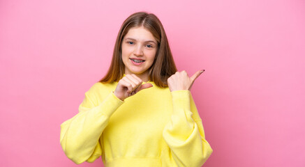 Teenager Russian girl isolated on pink background pointing to the side to present a product