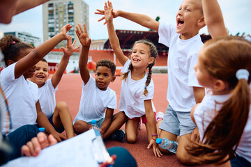 Cheerful group of kids have fun during sports training at stadium.