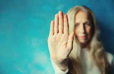 Upset young woman shows stop, no or enough sign with palm of hand, refusal gesture, domestic...
