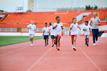 Group of children running during sport training at stadium.